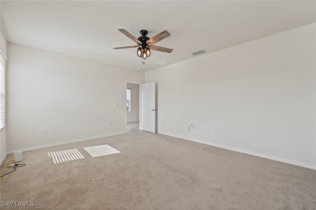 unfurnished room featuring a healthy amount of sunlight, light colored carpet, and ceiling fan