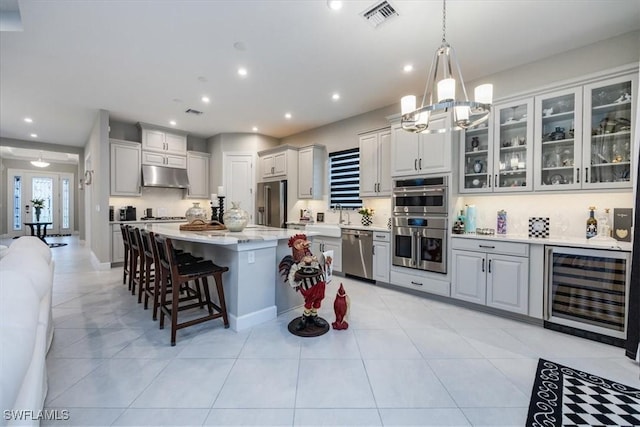 kitchen featuring appliances with stainless steel finishes, decorative light fixtures, wine cooler, backsplash, and a center island