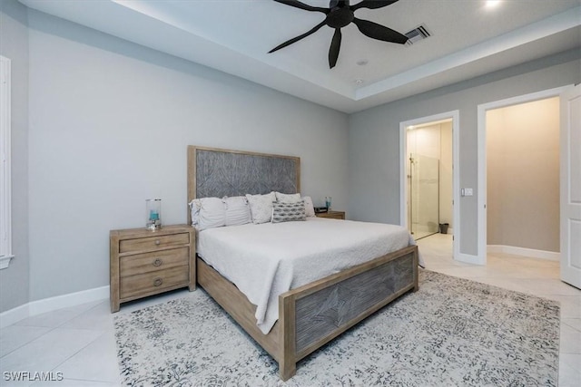 bedroom featuring ensuite bath, a raised ceiling, ceiling fan, and light tile patterned flooring