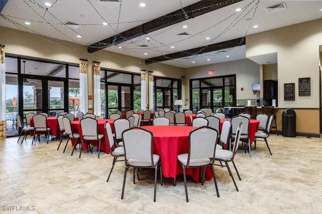 dining space with beamed ceiling, a high ceiling, and french doors