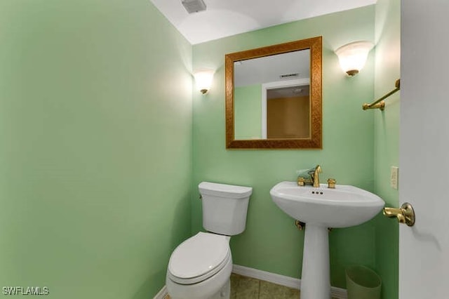 half bath featuring visible vents, baseboards, toilet, tile patterned flooring, and a sink