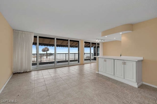 spare room featuring a wall of windows, baseboards, and light tile patterned floors