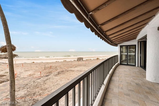 balcony with a water view and a beach view