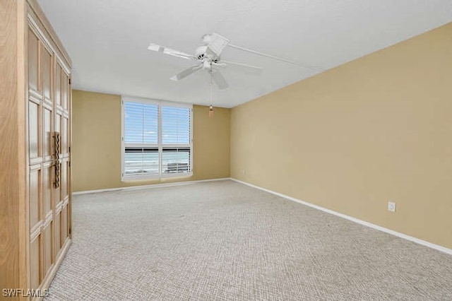 unfurnished room with light carpet, baseboards, and a ceiling fan