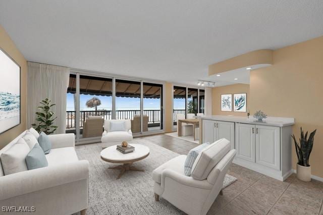 living area featuring light tile patterned floors, a wall of windows, and baseboards