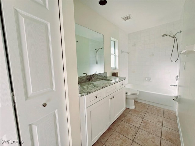 full bathroom featuring tile patterned flooring, vanity, tiled shower / bath, and toilet