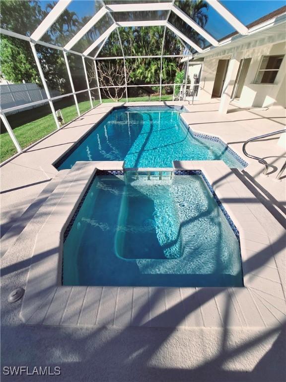 view of pool with an in ground hot tub, a patio, and glass enclosure