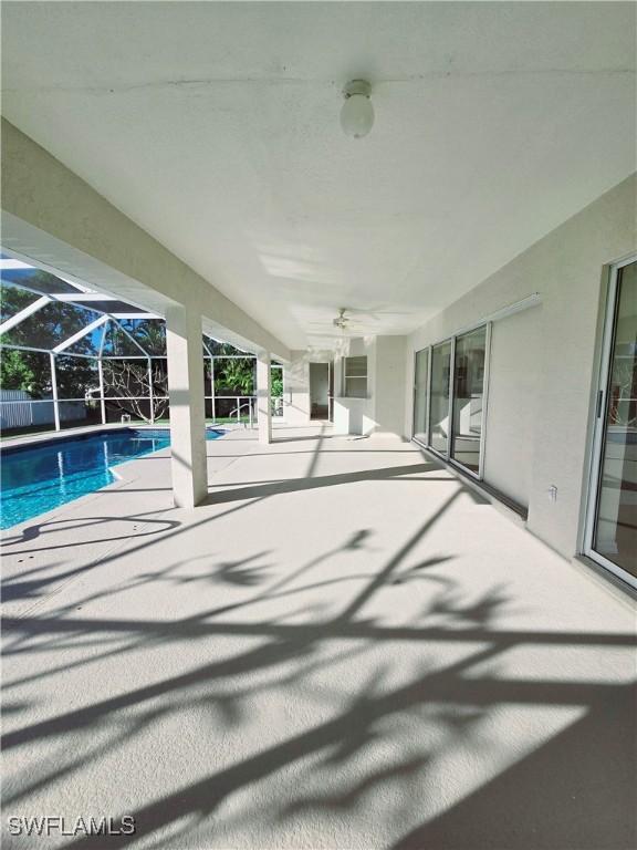 view of swimming pool with a patio, ceiling fan, and glass enclosure