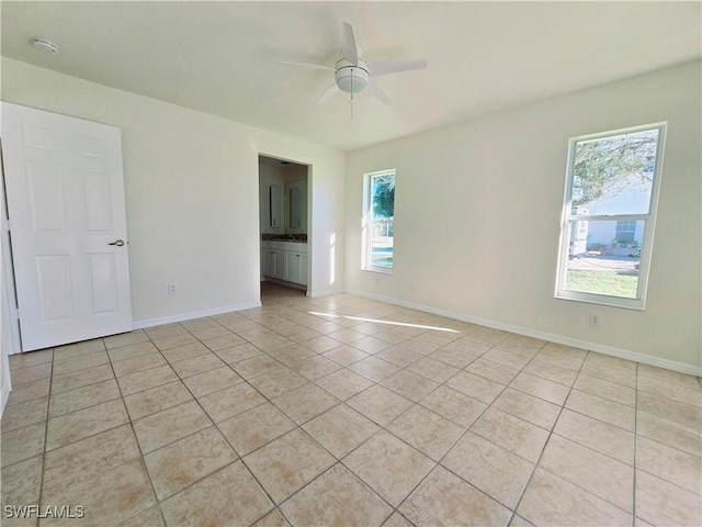 tiled empty room featuring ceiling fan