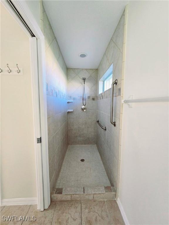 bathroom with tiled shower and tile patterned flooring