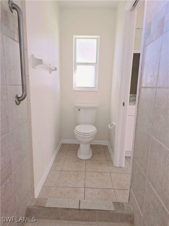 bathroom featuring tile patterned flooring, tiled shower, and toilet