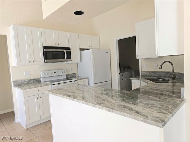 kitchen featuring sink, white cabinets, white appliances, light stone countertops, and washer and clothes dryer