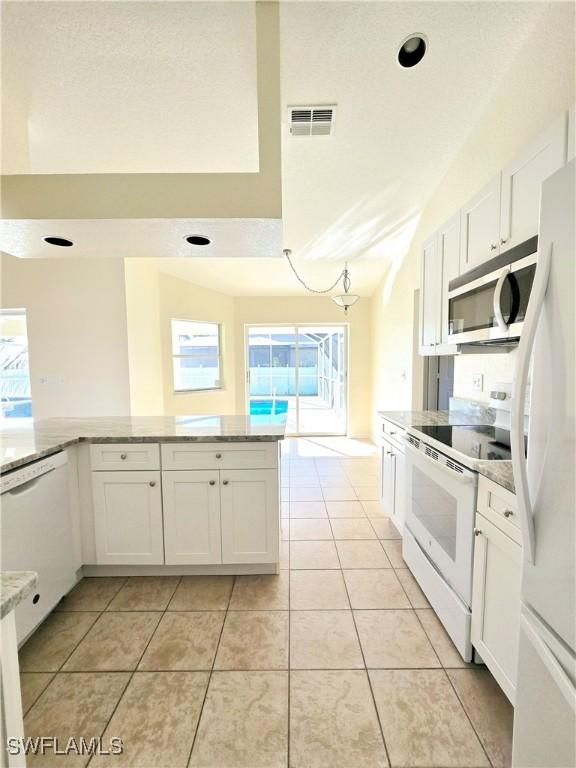 kitchen featuring white cabinetry, vaulted ceiling, light tile patterned floors, kitchen peninsula, and white appliances