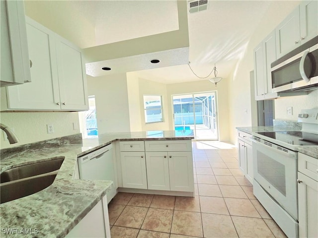 kitchen with light tile patterned floors, white cabinets, white appliances, and kitchen peninsula