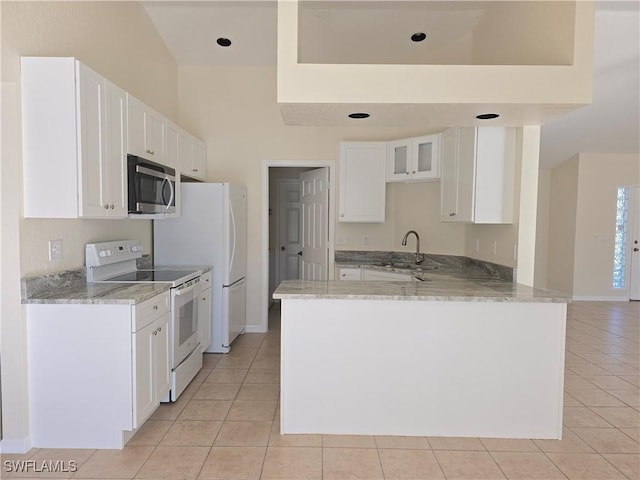 kitchen with light tile patterned flooring, light stone counters, kitchen peninsula, white appliances, and white cabinets