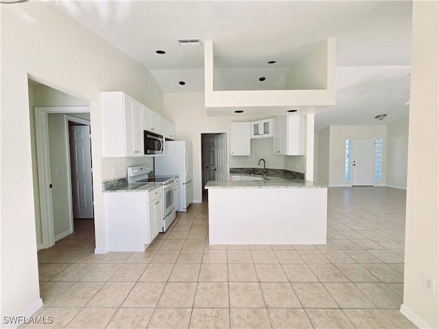 kitchen featuring light tile patterned floors, white appliances, kitchen peninsula, and white cabinets