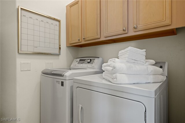 clothes washing area featuring washer and dryer and cabinets