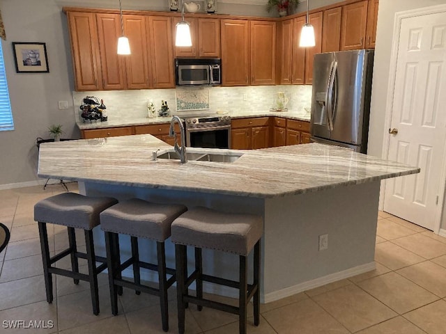 kitchen with hanging light fixtures, appliances with stainless steel finishes, sink, and light tile patterned floors