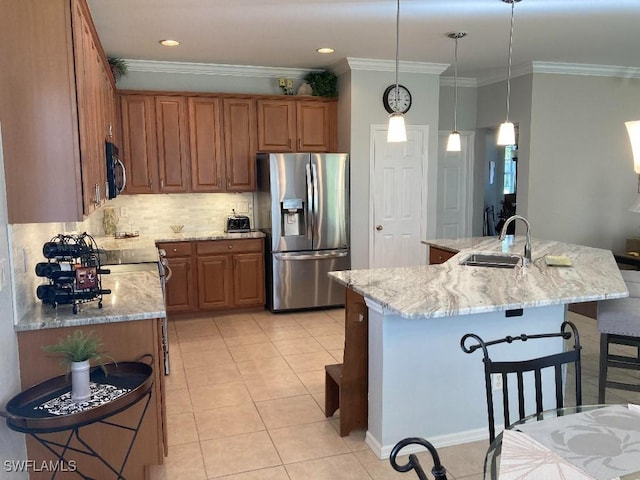 kitchen featuring appliances with stainless steel finishes, decorative light fixtures, sink, light stone countertops, and a center island with sink