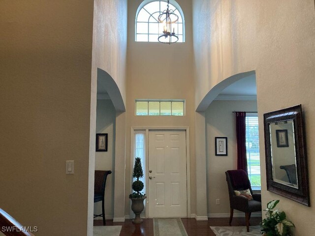 foyer featuring a notable chandelier, ornamental molding, and a high ceiling