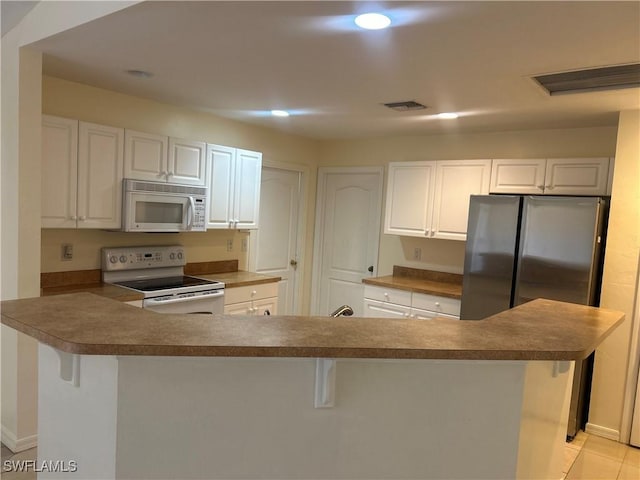 kitchen featuring white cabinetry, light tile patterned floors, white appliances, and a breakfast bar