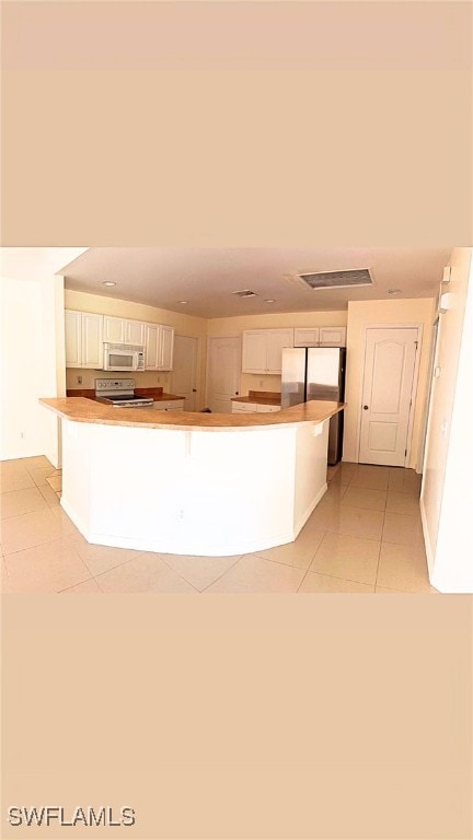 kitchen with white cabinetry, stainless steel refrigerator, kitchen peninsula, and electric range