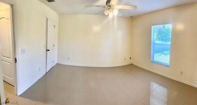 spare room featuring ceiling fan, light tile patterned floors, and a healthy amount of sunlight