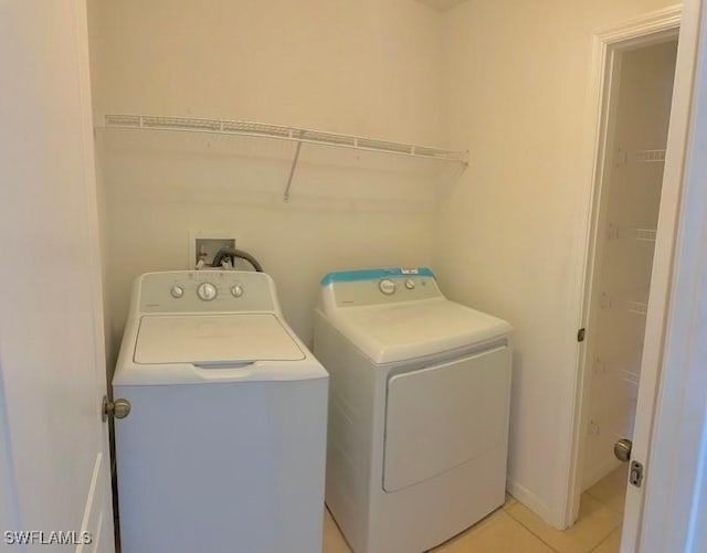 clothes washing area featuring light tile patterned floors and washer and clothes dryer