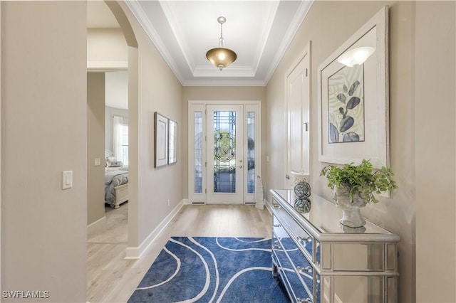 entrance foyer with a raised ceiling, crown molding, and light hardwood / wood-style flooring