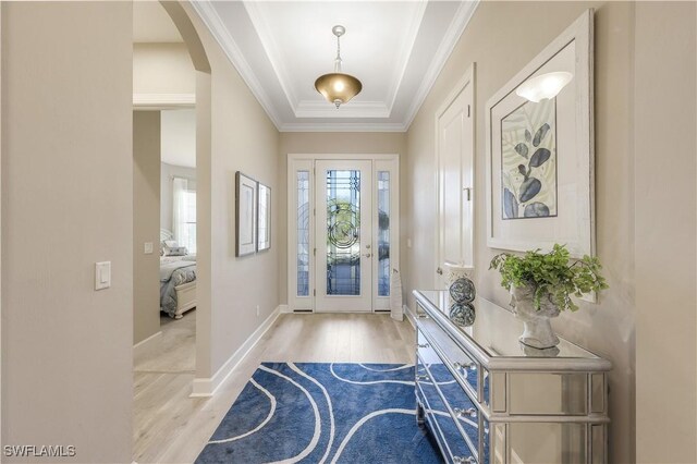 foyer with a raised ceiling, crown molding, and light hardwood / wood-style floors