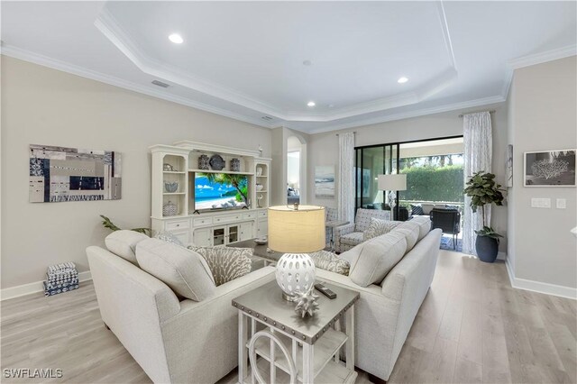 living room featuring crown molding, a raised ceiling, and light hardwood / wood-style floors