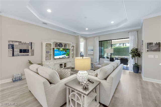 living room with crown molding, a raised ceiling, and light wood-type flooring