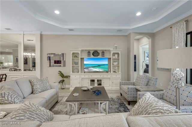 living room with crown molding, a tray ceiling, and light hardwood / wood-style floors