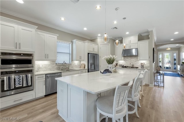 kitchen featuring a kitchen island, appliances with stainless steel finishes, hanging light fixtures, and white cabinets