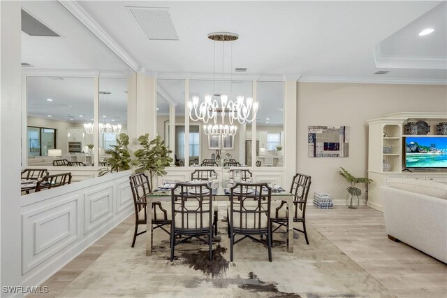 dining room with a notable chandelier, ornamental molding, and light hardwood / wood-style floors