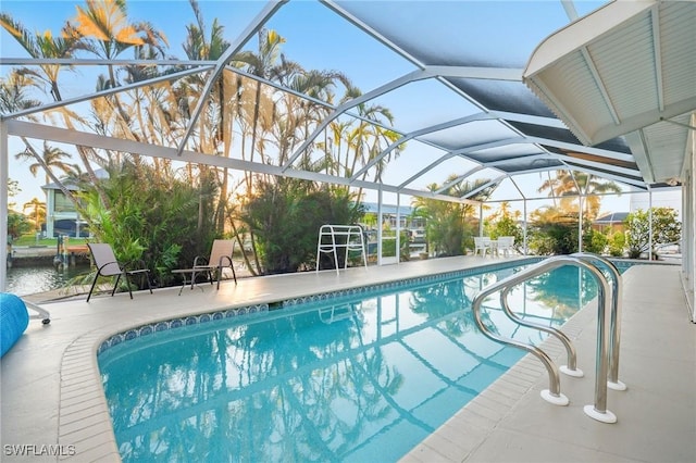 view of pool featuring a patio area, a water view, and glass enclosure