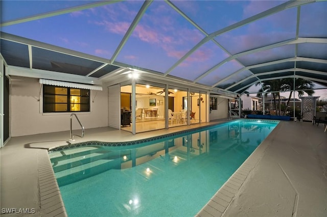 pool at dusk featuring a lanai and a patio