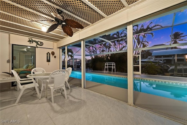 pool at dusk featuring a lanai, a patio area, and ceiling fan