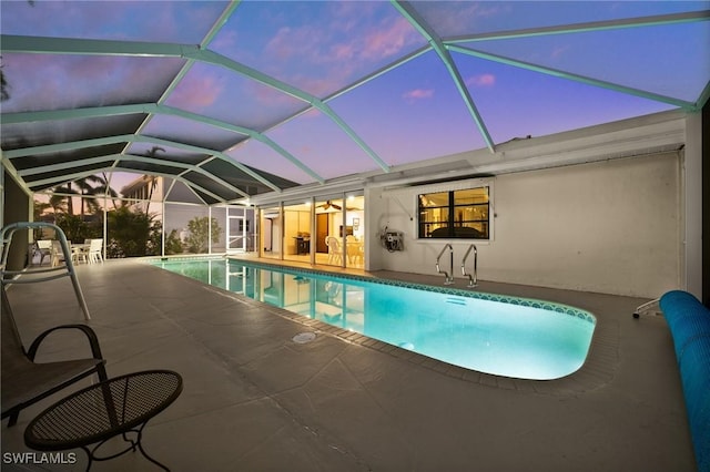 pool at dusk with a lanai and a patio area