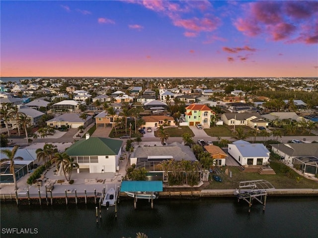 aerial view at dusk featuring a water view