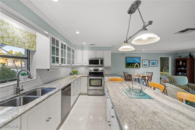 kitchen featuring sink, hanging light fixtures, stainless steel appliances, light stone countertops, and white cabinets