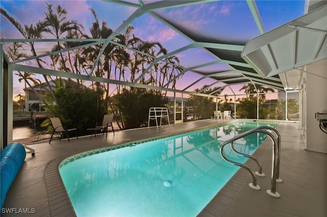 pool at dusk with a patio and glass enclosure