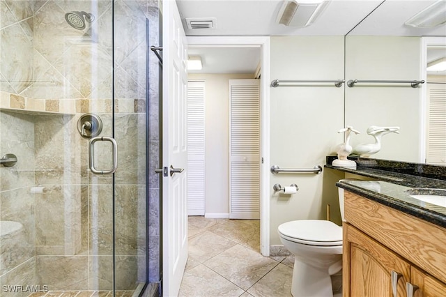 bathroom with a shower with door, vanity, tile patterned floors, and toilet