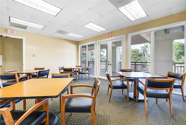 carpeted dining area featuring a drop ceiling and french doors