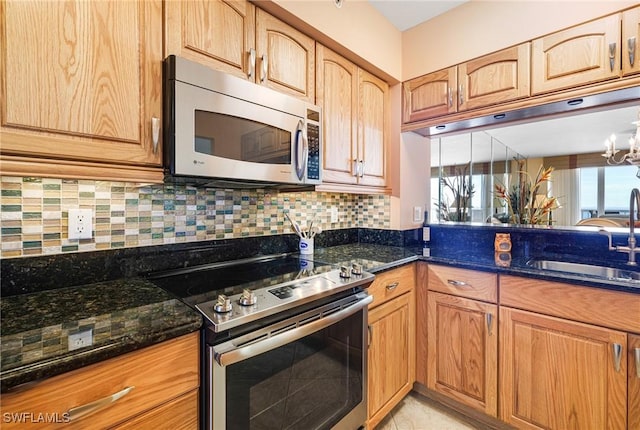 kitchen with dark stone countertops, sink, backsplash, and appliances with stainless steel finishes