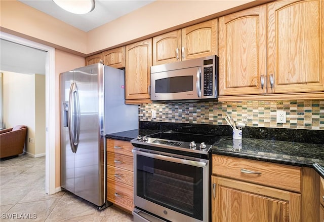 kitchen featuring appliances with stainless steel finishes, dark stone countertops, and backsplash