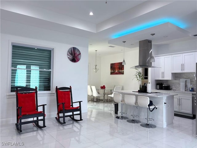 kitchen featuring hanging light fixtures, island exhaust hood, a kitchen island, and white cabinets