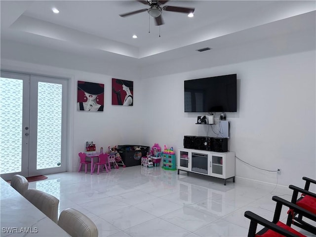 living room featuring a tray ceiling, plenty of natural light, and ceiling fan