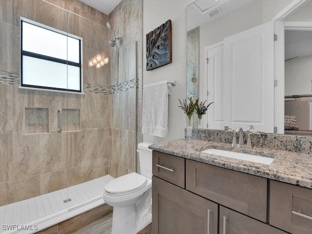 bathroom featuring vanity, a tile shower, and toilet