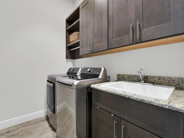 laundry area featuring sink, cabinets, washer and dryer, and light wood-type flooring